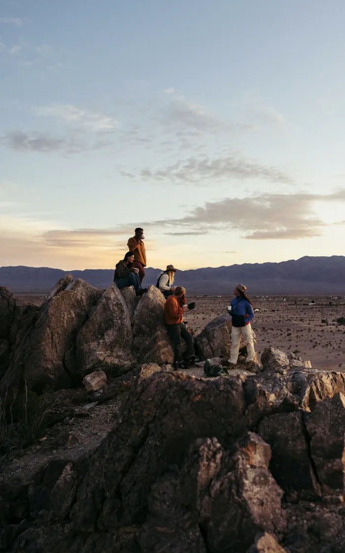 Teammates gathered on desert rocks at sunset